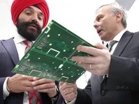 Hon. Navdeep Bains, left, Minister of Innovation, Science and Economic Development and Mariusz Olszowik of APAG Elektronik inspect an electronic control system panel during a $5-million funding announcement at the APAG plant on Rhodes Drive Monday, Jan. 14, 2019.