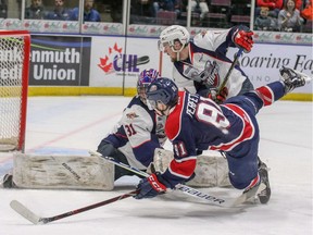Windsor Spitfires' defenceman Connor Corcoran tries to hold off Saginaw Spirit forward Cole Perfetti in front of Windsor goalie Colton Incze during Sunday's OHL game at the Dow Event Center.