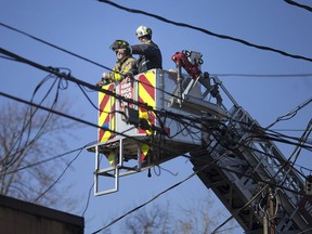 An investigator with Ontario's Office of the Fire Marshal gets a lift by a member of the Windsor Fire and Rescue Services on Jan. 4, 2019, to help survey fire damage following a major blaze at the El-Mayor Restaurant.