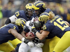 FILE - In this Nov. 25, 2017, file photo, Ohio State quarterback J.T. Barrett (16) is sacked by Michigan defensive linemen Rashan Gary (3) and Chase Winovich (15) during the second half of an NCAA college football game in Ann Arbor, Mich.