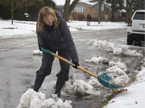 Cheryl Cross-Leal removes melting snow from the curb in front of her home on Woodlawn Avenue to avoid flooding as the snow melts on a mild Jan. 23,  2019.