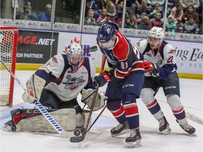 Windsor Spitfires goalie Kari Piiroinen stops Saginaw Spirit forward Cole Perfetti while Windsor defenceman Thomas Stevenson chases on the play during Saturday's game at the Dow Event Center.