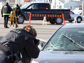 A Windsor police forensics officer photographs evidence after a female pedestrian was struck by a vehicle on Teumseh Road East on  the morning Dec 18.