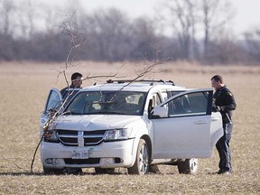 Essex County OPP officers examine a white crossover SUV that was driven into a farmer's field, then abandoned by the motorist on Jan. 11, 2019.