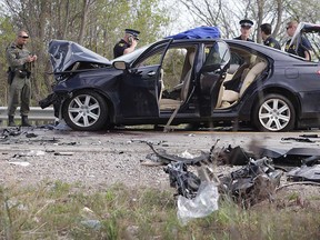 Essex County OPP officers examine the dark-coloured Lexus that collided with another vehicle on Highway 3 on April 26, 2017. The driver of the vehicle, Satvir Singh, and his passenger, Tariq Elamin, were both found to be armed with guns.