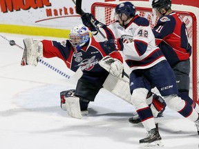 Windsor, Ontario. February 7, 2019 -   Windsor Spitfires goaltender Kari Piiroinen, left, concentrates on the puck as Spits Sean Allen battles with Saginaw Spirit Jake Goldowski in OHL action from WFCU Centre February 7, 2019.