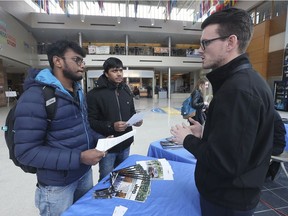 Gowrish Kothandaraman, left, and Gopi Rajendran, both engineering students at the University of Windsor, speak with Austin Garant, a human resources representative from Fiat Chrysler Automobiles, on Tuesday, February 26, 2019, at the CAW Centre on campus.