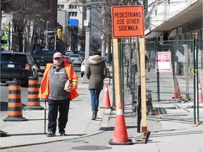 Pedestrian John Harling, left, and others had to walk around small construction sites on east sidewalk of Ouellette Avenue Tuesday.  Harling had no issue with the small detour.