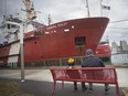 Emerson Silva, 7, and his father, Tom Silva, take a break on a bench at Dieppe Park while the Canadian Coast Guard vessel, the CCGS Samuel Risley, sits docked Thursday, March 14, 2019.