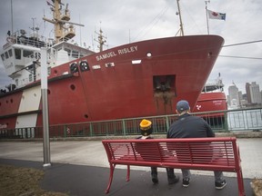 Emerson Silva, 7, and his father, Tom Silva, take a break on a bench at Dieppe Park while the Canadian Coast Guard vessel, the CCGS Samuel Risley, sits docked Thursday, March 14, 2019.