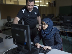 Mae Muflahi, 16, a Grade 11 student at Riverside secondary school, receives some help from principal Tony Omar while in the computer lab on March 21, 2019.