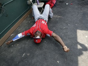 Washington Nationals' Victor Robles keeps loose by stretching in the dugout between innings of an exhibition spring training baseball game against the Miami Marlins Monday, March 4, 2019, in Jupiter, Fla.