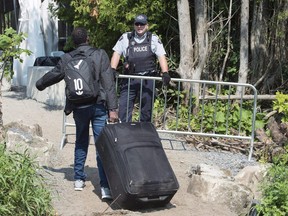 An asylum seekers, claiming to be from Eritrea, is confronted by an RCMP officer as he crosses the border into Canada from the United States on August 21, 2017 near Champlain, N.Y. The federal government has been warned to take a cautious approach to publicly debating immigration over fears of reaching a "tipping point" that could undermine the public's support for welcoming immigrants into the country. Internal data prepared by the Immigration Department for a committee of deputy ministers shows a majority of Canadians support current immigration levels, but this support drops when they are informed of how many immigrants actually come to Canada every year.