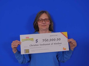 Christine Dowhaniuk of Windsor holds up the $250,000 prize cheque she won from playing Instant Crossword Deluxe, March 18, 2019.