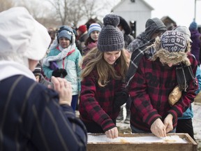 People line up for maple taffy on snow at the John R. Park Homestead Maple Syrup Festival, Saturday, March 2, 2019.