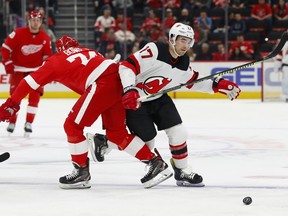 Detroit Red Wings defenseman Madison Bowey (74) checks New Jersey Devils left wing Kenny Agostino (17) off the puck during the first period of an NHL hockey game Friday, March 29, 2019, in Detroit.