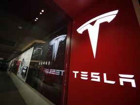 FILE- In this Feb. 9, 2019, file photo, a sign bearing the company logo is displayed outside a Tesla store in Cherry Creek Mall in Denver.