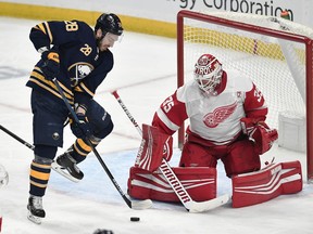 Buffalo Sabres center Zemgus Girgensons, left, tries to deflect the puck past Detroit Red Wings goalie Jimmy Howard during the third period of an NHL hockey game in Buffalo, N.Y., Thursday, March 28, 2019. Detroit won 5-4 in overtime.