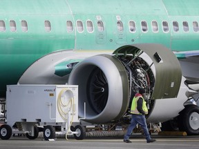 FILE- In this March 13, 2019, file photo a worker walks past an engine on a Boeing 737 MAX 8 airplane being built for American Airlines at Boeing Co.'s Renton assembly plant in Renton, Wash. U.S. prosecutors are looking into the development of Boeing's 737 Max jets, a person briefed on the matter revealed Monday, the same day French aviation investigators concluded there were "clear similarities" in the crash of an Ethiopian Airlines Max 8 last week and a Lion Air jet in October.