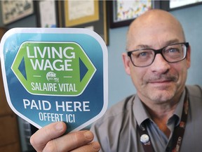 Neil Mackenzie, a manager of health promotion with the Windsor-Essex County Health Unit, holds up a decal for the Living Wage campaign on March 1, 2019.