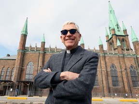 Father Maurice Restivo stands in front of Our Lady of the Assumption Church on April 5, 2019. Starting roof repairs this month on the historic 174-year-old landmark on Huron Church Road paves the way for a hoped-for re-opening in the fall.
