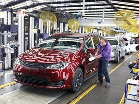 In this Dec. 7, 2018, file photo, inspector Frank Calzavara is shown with a Chrysler Pacifica Hybrid in velvet red in the Final Car area of FCA Windsor Assembly Plant.