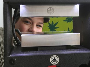 Alicia Jimmerfield, known as the Squishy Hippie, poses with her mobile rosin press, which produces cannabis extract, on Saturday April 20, 2019 at Ford City's Pretty Baked, a new cannabis accessory shop celebrating its first 4/20 in business.
