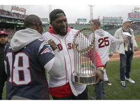 New England Patriots' Matthew Slater, left, clasps hands with former Boston Red Sox star David Ortiz as he holds the World Series trophy before the home opener baseball game between the Red Sox and the Toronto Blue Jays, Tuesday, April 9, 2019, in Boston. At right are former Red Sox star Mike Lowell (25) and retired New England Patriots' Rob Gronkowski, far right.