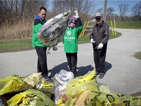 In this April 13, 2019, file photo, Dale Sandison, left, and his father, Gary Sandison, watch as Dale's son Rory tosses a bag of trash they collected in with the rest of the garbage during a Ganatchio Trail cleanup honouring attack victim Anne Widholm. Widholm frequently walked the trail, cleaning up garbage left by others.