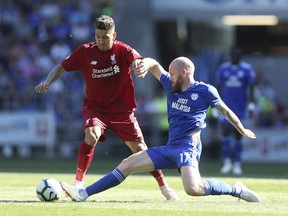 Liverpool's Roberto Firmino and Cardiff City's Aron Gunnarsson, right, battle for the ball during the English Premier League soccer match at The Cardiff City Stadium, Cardiff, Wales, Sunday April 21, 2019.