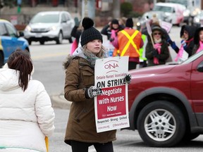 A striking member of Ontario Nurses' Association Local 8 holds a placard outside the Windsor-Essex County Health Unit offices on Ouellette Avenue on April 4, 2019.
