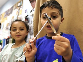 Using a tuning fork, twins Gregoris, right, and Zoe Senteris, 5, participate in the Music Making challenge during 'A World of Motion' STEM Expo at St Anne French Immersion Elementary School on May 7, 2019. Mme. Katerina Lucier (not shown) supervised students in the Making Music room.