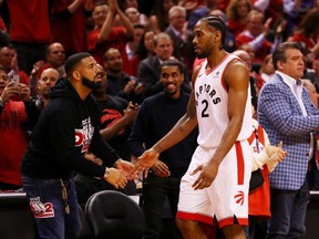 TORONTO, ONTARIO - MAY 21: Kawhi Leonard #2 of the Toronto Raptors high fives rapper Drake during game four of the NBA Eastern Conference Finals between the Milwaukee Bucks and the Toronto Raptors at Scotiabank Arena on May 21, 2019 in Toronto, Canada. NOTE TO USER: User expressly acknowledges and agrees that, by downloading and or using this photograph, User is consenting to the terms and conditions of the Getty Images License Agreement.