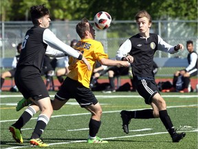 Windsor, Ontario. May 23, 2019. Kennedy Clippers Otis Vacratsis, centre, breaks through Riverside defenders Aleksandar Simonovski, left, and Denis Nuhanovic in the first half at Holy Names Field Thursday.   See Parker story.