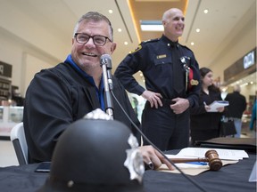 Joe McParland, left, plays the role of judge during a mock trial for the Crime Stoppers fundraiser, Bail or Jail, while Police Chief, Al Frederick looks on, at Devonshire Mall, Thursday, May 9, 2019.