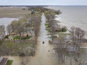 A truck slowly drives through a flooded Cotterie Park Rd., as waves batter the shore of Lake Erie along Cotterie Park Rd., Wednesday, May 8, 2019.