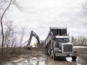 An excavator pushes around sand delivered by a dump truck at Hillman Marsh Beach on May 8, 2019. High lake levels have eroded large portions of the beach.