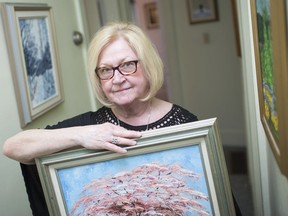 Sister Janine Rocheleau, shown May 6, 2019, holds one of Father Joe Quinn's paintings, with other artworks he created hanging on the walls at Marie Rose Place in Windsor.