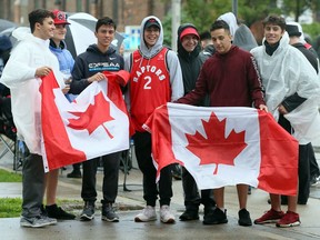 The initial rain couldn't prevent Toronto Raptors fans Massimo Caruso, left, Steven Reinhart, right, and a handful of their friends from waving the flag at Jurassic Park Windsor on Thursday night. While the first quarter might have been a washout, with organizers temporarily shutting down the event, the skies soon cleared and an estimated 1,000 or more Raptors fans eventually crowded into Charles Clark Square for Game 6 of the NBA Finals series.