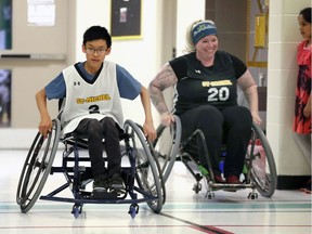 Ecole St. Michel Grade 7 student Wilson Tran, left, participates in a teacher vs. student basketball game organized by health and physical education teacher Serrah Gossmann, right.  Since Monday, students have been playing different sports, all modified for wheelchair users.  They were given the opportunity to experience being active from the perspective of physically challenged persons. Teachers won the wheelchair basketball game 18-16.
