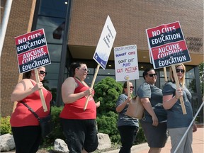 Windsor, Ontario. June 18, 2019.  OSSTF members walk with protest signs against job cuts in front of the Greater Essex County School Board offices on Park Street West.  The "No Cuts to Education" rally attracted dozens of protestors and local MPP Percy Hatfield (not shown).
