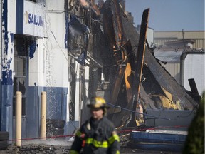 A Windsor firefighter walks past the aftermath of a large commercial fire at Serbu Tire, 1597 Howard Ave., on June 23, 2019.