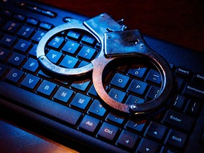 A stock image of handcuffs on a computer keyboard.