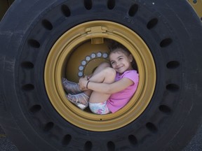 Katarina Morgan, 7, curls up inside the wheel of an excavator at the 9th annual Meet-A-Machine in the WFCU Centre parking lot, Saturday, June 22, 2019.