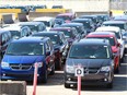 In this March 27, 2019, photo, Dodge Grand Caravans are shown parked alongside Chrysler Pacificas manufactured at FCA Canada's Windsor Assembly Plant awaiting their transportation to consumers.