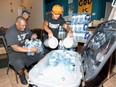 Street Help's Anthony Nelson and Dan Druer, right, load bottled water and ice into a large cooler at Street Help Homeless Centre Saturday.  Area homeless and residents without air conditioning dropped in for a visit to cool off and enjoy a refreshing drink.