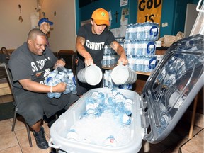 Street Help's Anthony Nelson and Dan Druer, right, load bottled water and ice into a large cooler at Street Help Homeless Centre Saturday.  Area homeless and residents without air conditioning dropped in for a visit to cool off and enjoy a refreshing drink.