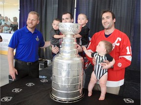 Steve Ott, left, graciously poses with Jeff Lachance holding twin sons, Noah and Liam, 21 months old, and Uncle Jason Lachance, right, holding Benny, 9 months old at Atlas Tube Centre Sunday.  Hundreds lined up for opportunity.
