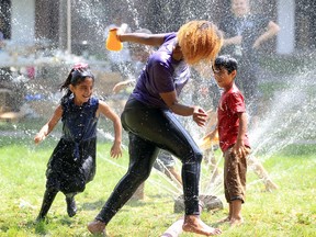 Funner Day participant Farmat, 8, left, chases Glengarry camp senior Tracey Jean, centre, around Windsor Fire Services' fire hose during Tuesday's festivities held by The Glengarry Community Lighthouse.  The wet and wild fun was just one of the activity stations located in the Glengarry courtyard.