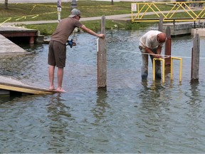 Hotte Marine workers Derek Rocheleau, left, and Neil Maure take measurements of the submerged boat ramp dock at Belle River Marina Wednesday. Lakeshore Council voted to increase the height of the dock and the boat ramp will remain open to boaters.